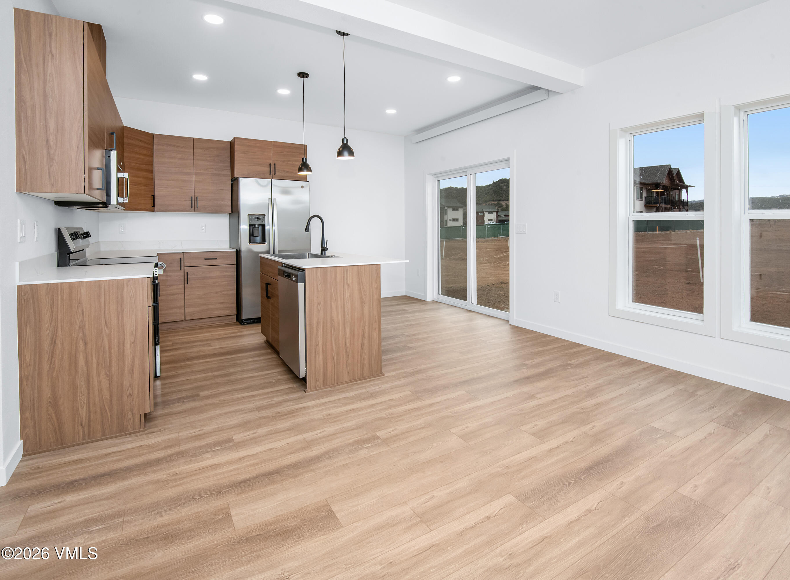 Vacant kitchen with wood cabinets, stainless steel appliances, and large windows overlooking the yard.
