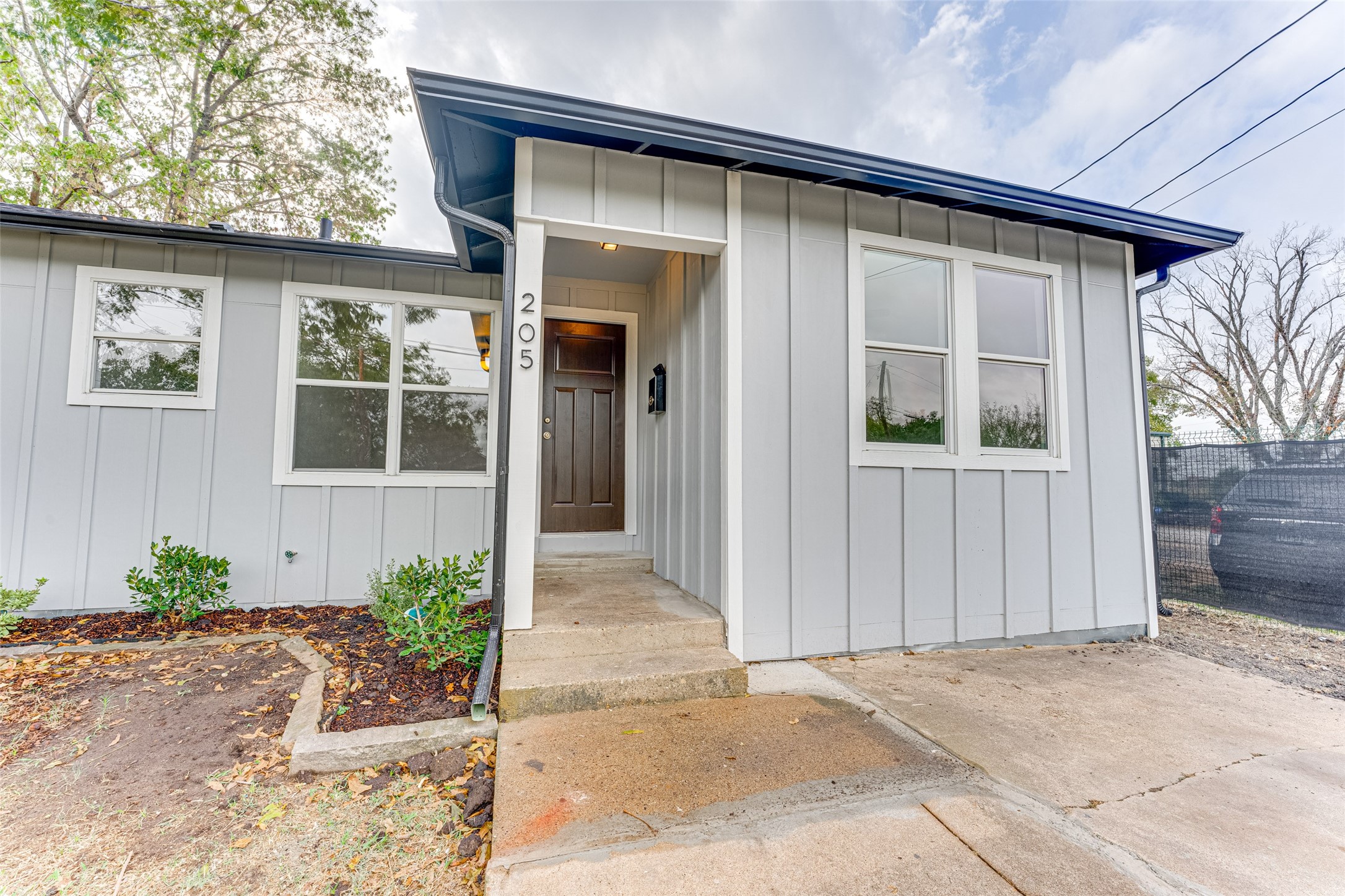 Gray-sided home with blue roof trim and a recessed entry marked 205.