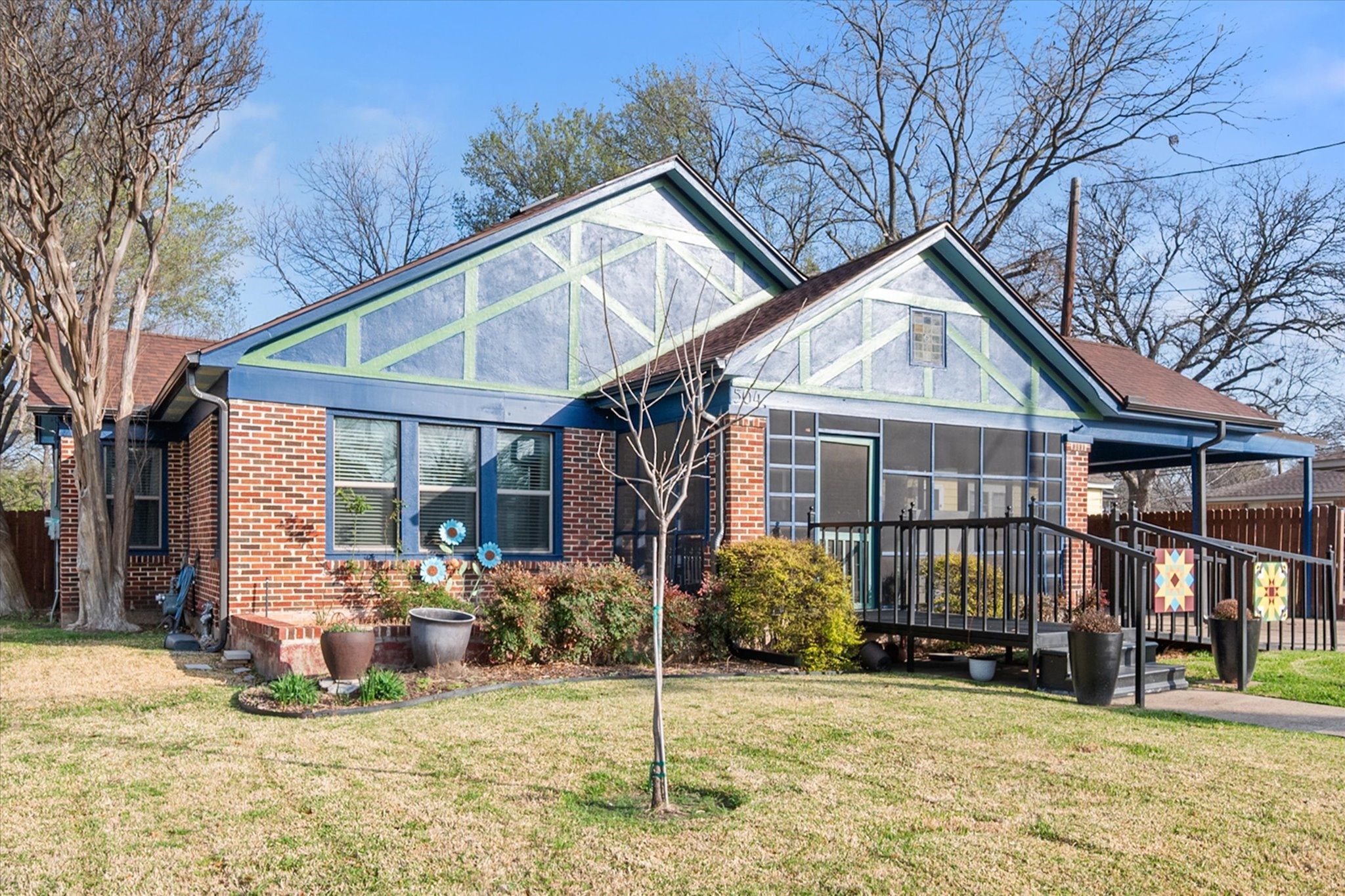 Red-brick house with blue and pale-green gables, screened porch, and wheelchair ramp.