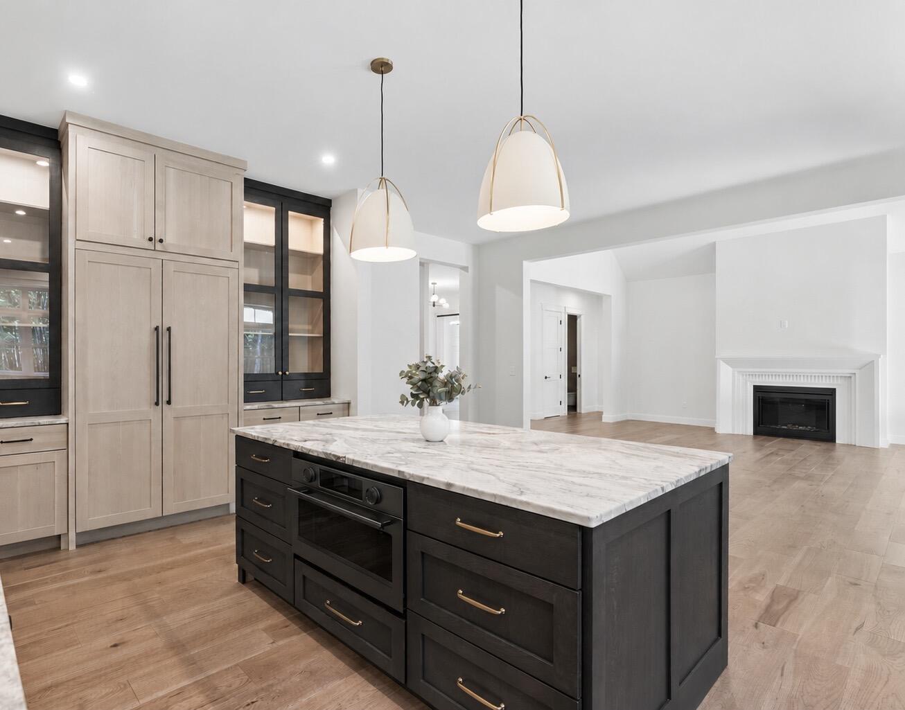 Kitchen with a marble island, dark cabinetry, and adjoining living area fireplace.