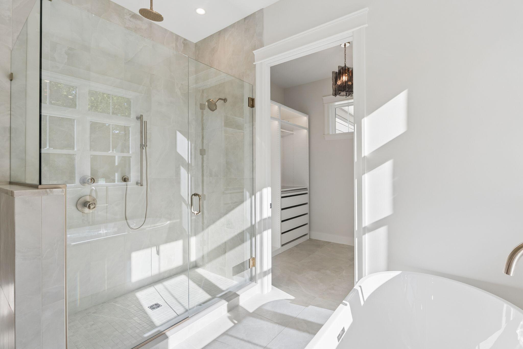 Primary bathroom with a glass-enclosed tiled shower, soaking tub, and doorway to a walk-in closet.