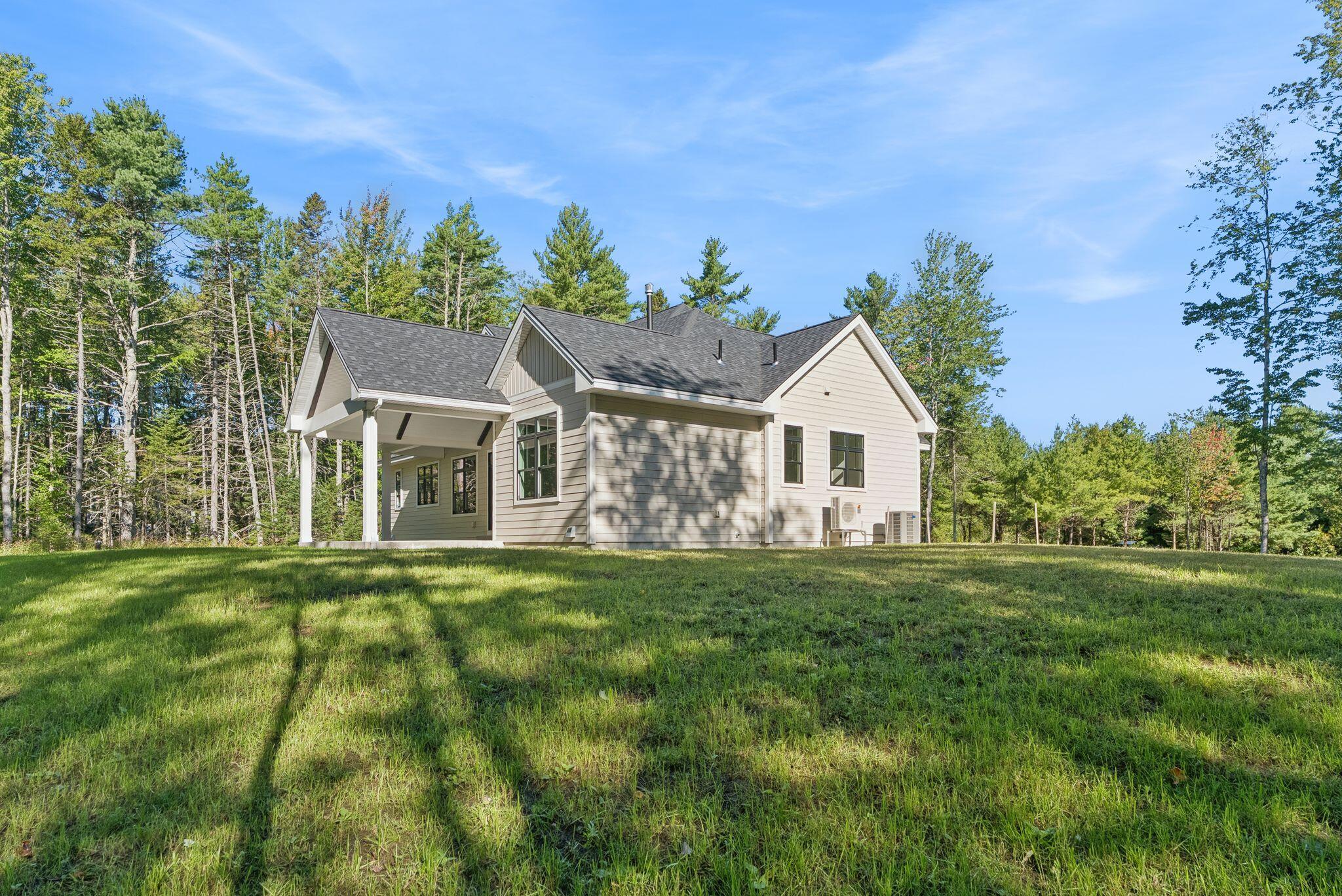 Light-colored house with a covered porch and gray gabled roof on a grassy lawn.