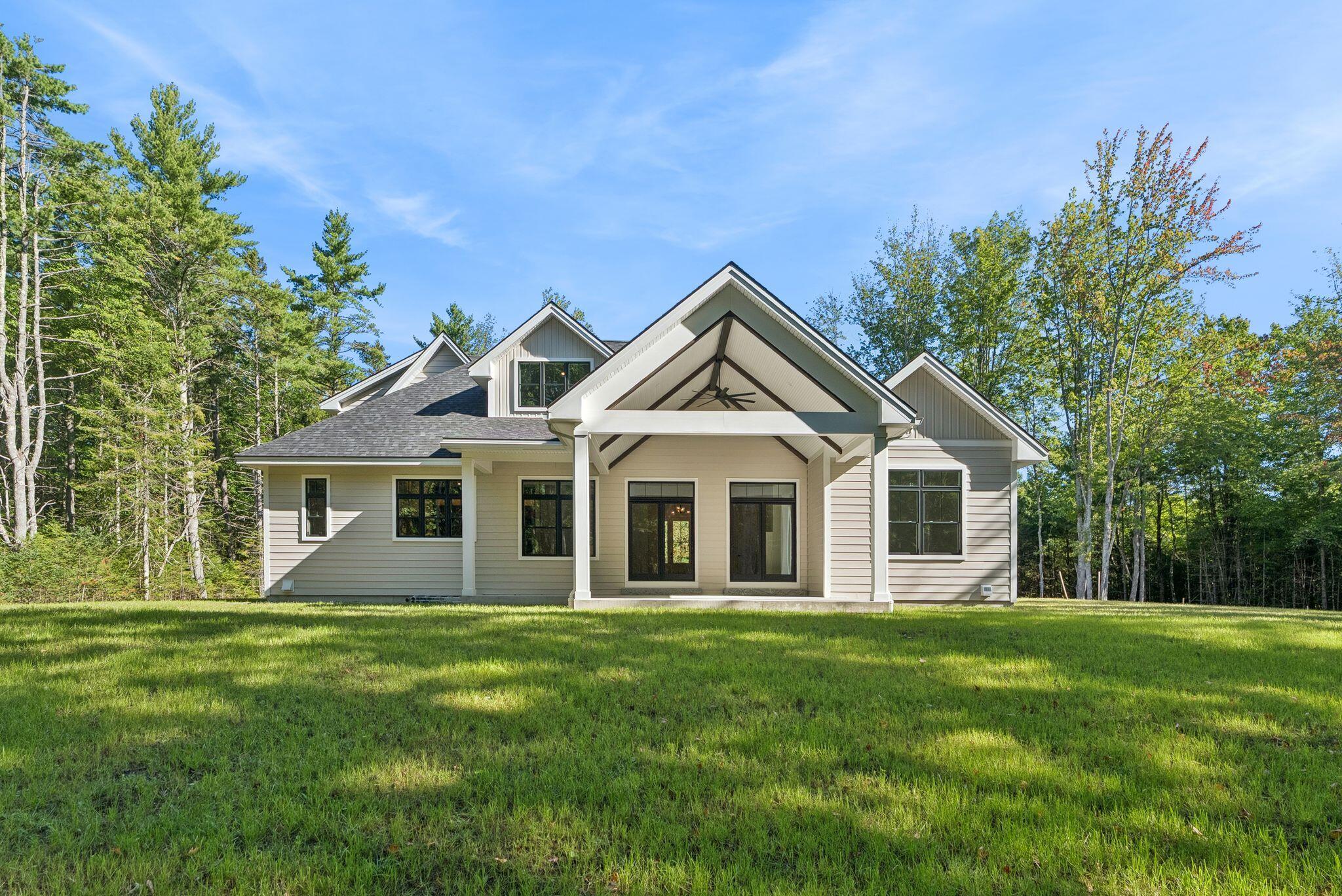 Home with multiple gables and covered entry, surrounded by trees and a broad green lawn.
