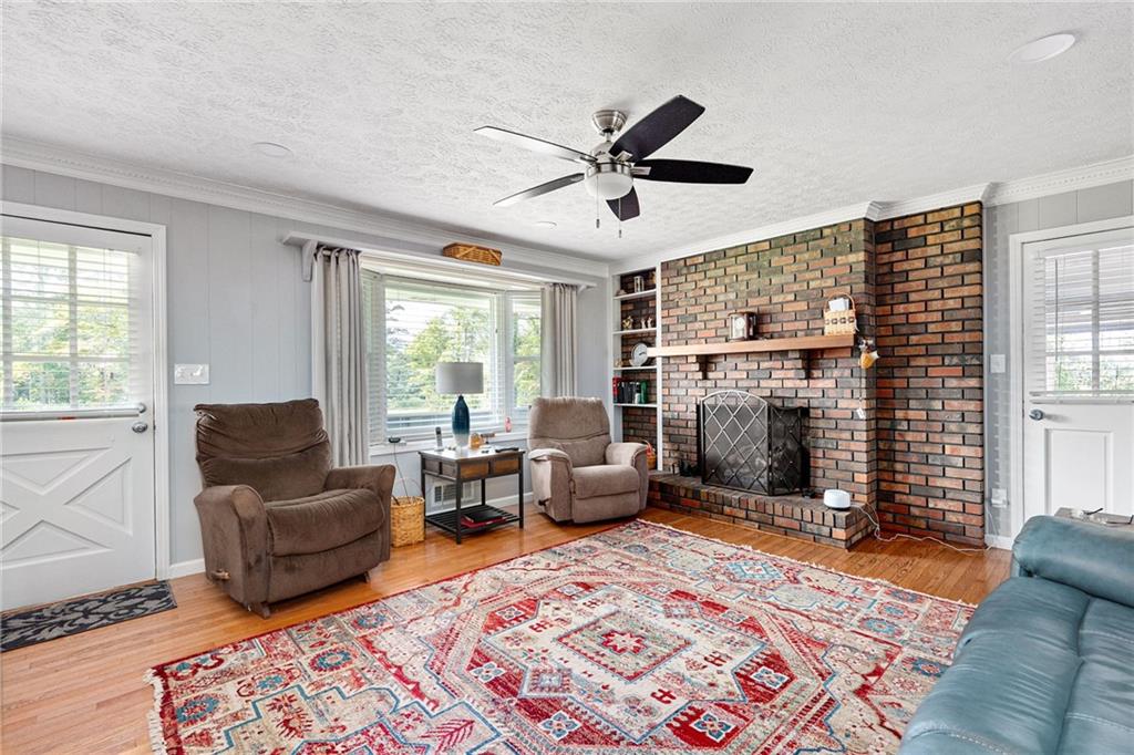 Living room with a brick fireplace, brown recliners, and a colorful patterned rug.