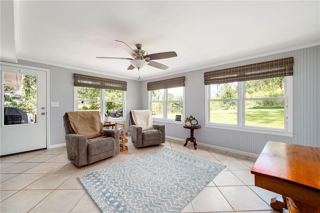 Furnished sitting room with two recliners, large windows overlooking a lawn, and a patterned rug.
