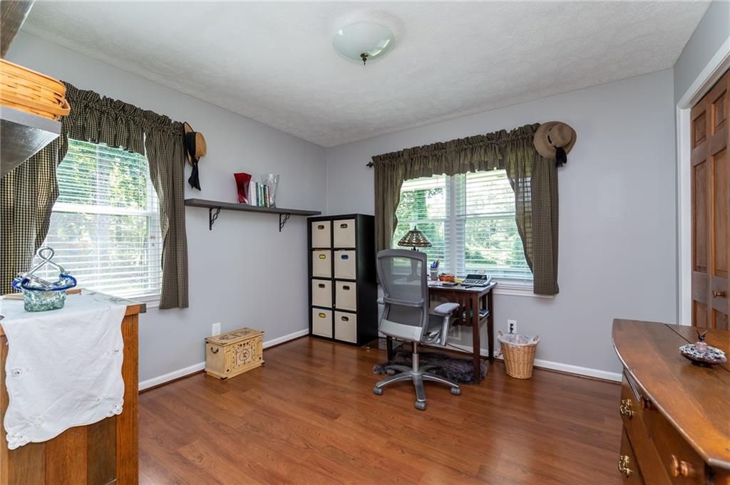 Home office with hardwood floors, two curtained windows, a desk, and cube storage.