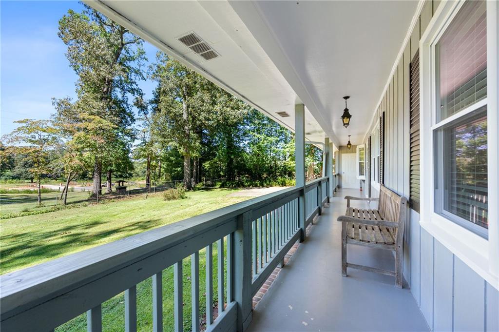 Covered front porch with green railing, wooden rocking chairs, and a view of the tree-lined lawn.