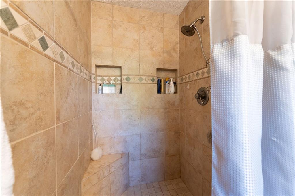 Tiled walk-in shower with a built-in bench, recessed toiletry niches, and a decorative accent band.