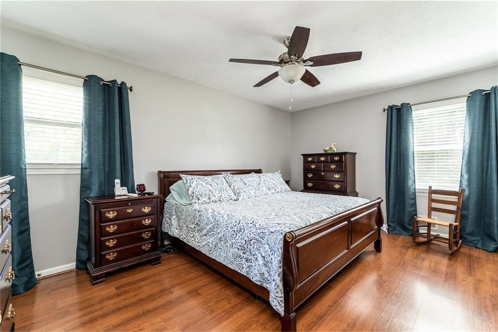 Bedroom with a dark wood bed, matching dressers, hardwood floors, and teal curtains.