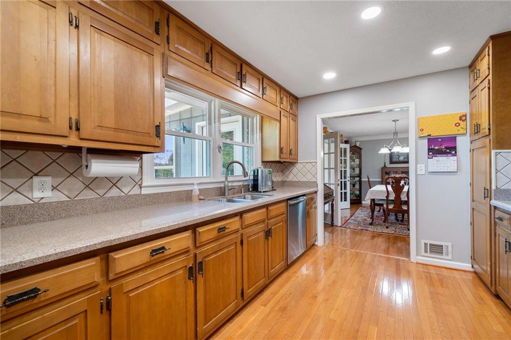 Kitchen with honey-toned cabinets, a long countertop, and a doorway to the dining room.