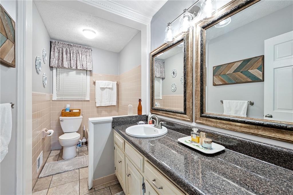 Bathroom with a long granite vanity, framed mirrors, and a separate toilet area.