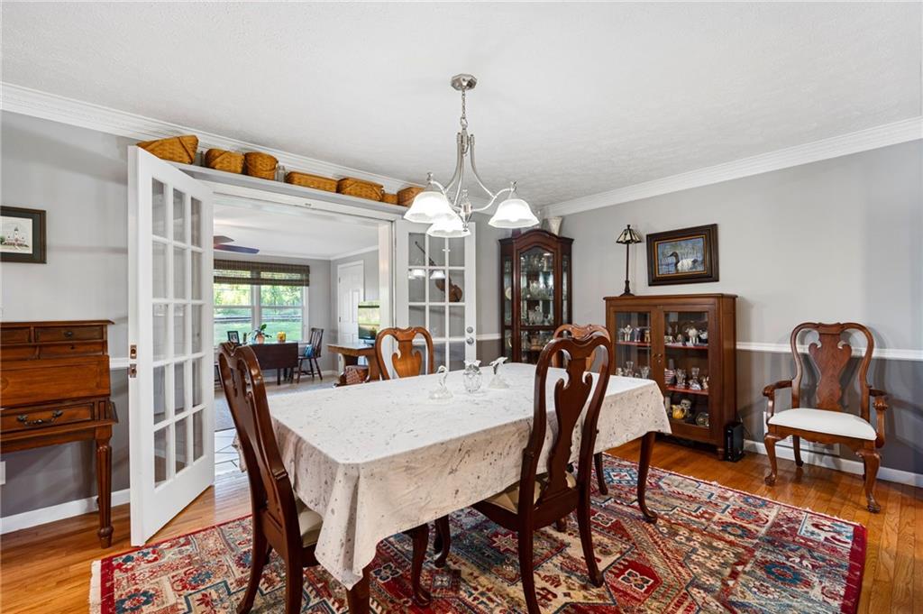 Dining room with carved wooden chairs, a patterned rug, and French doors to a breakfast area.