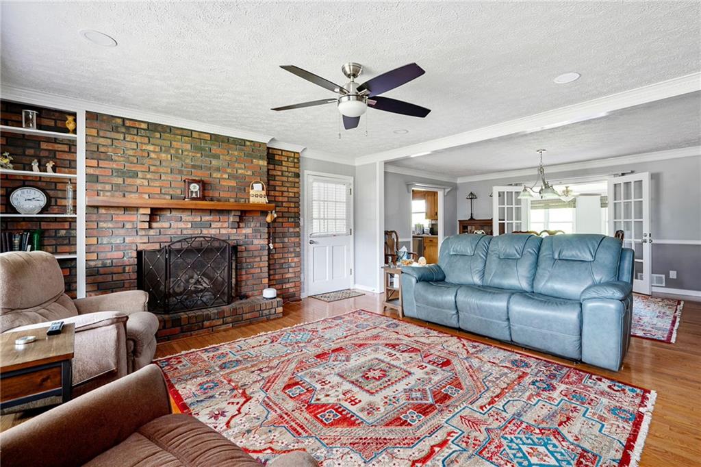 Living room with a brick fireplace, built-in shelves, blue leather sofa, and colorful patterned rug.