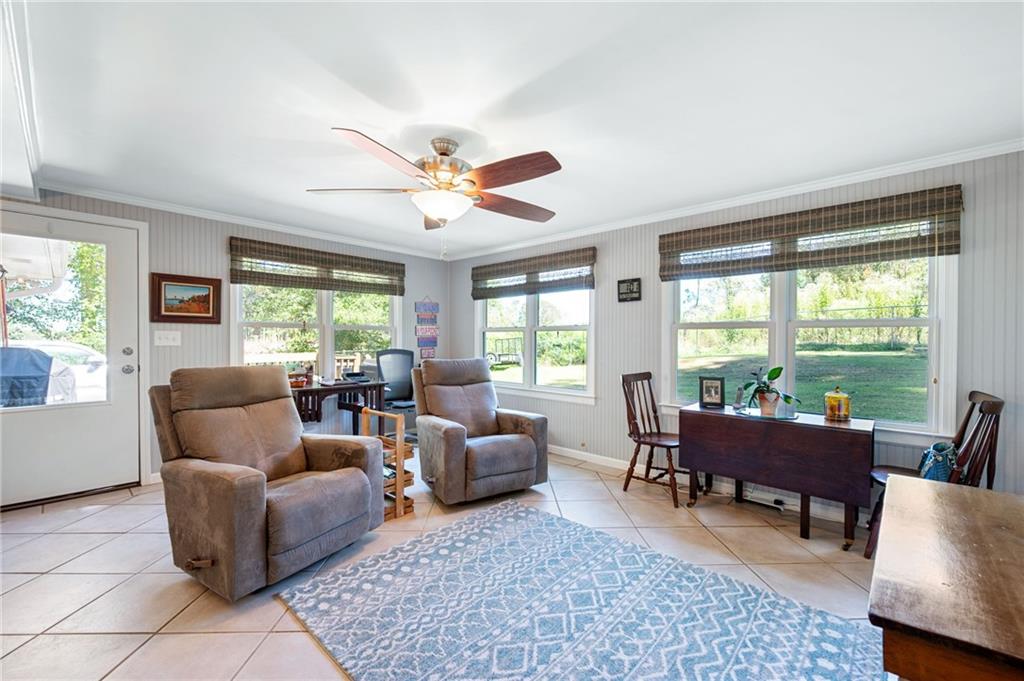 Furnished living room with recliners, a blue patterned rug, and large windows overlooking a green yard.