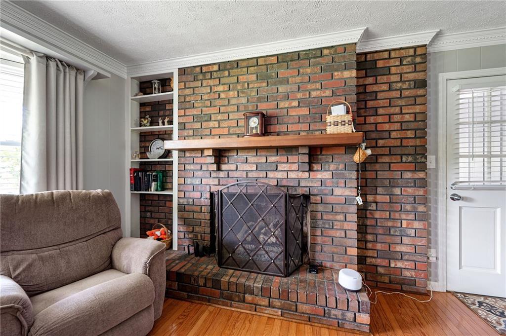 Living room with a large brick fireplace, raised hearth, built-in shelves, and brown recliner.