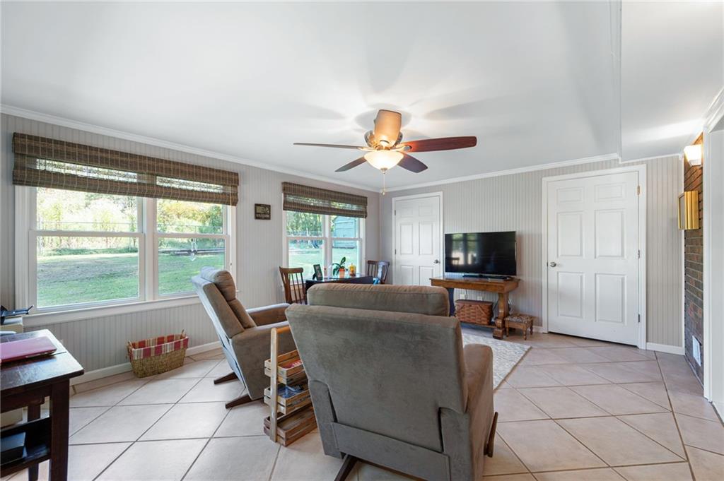 Living room with gray recliners, large yard-facing windows, and a ceiling fan.
