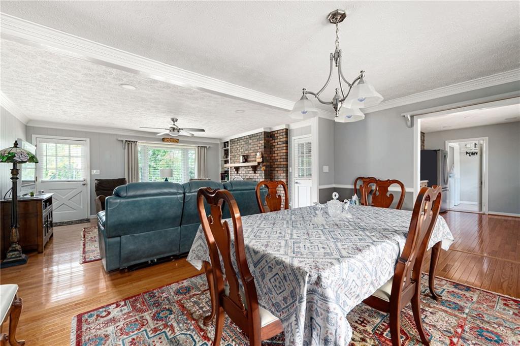 Dining and living room with hardwood floors, a brick fireplace, and large windows.
