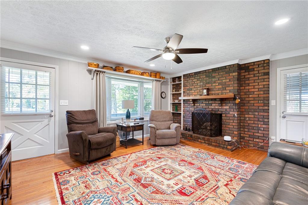 Living room with a brick fireplace, built-in shelves, and a colorful patterned rug.