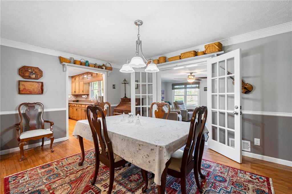 Dining room with a large table, dark wood chairs, chandelier, and open French doors to the living room.