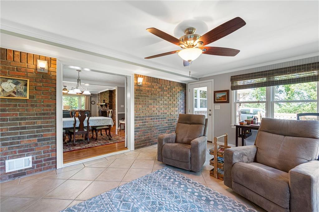 Living room with brick walls, tan leather recliners, a ceiling fan, and an adjoining dining room.