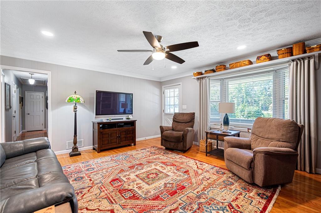 Living room with a patterned rug, leather sofa, recliners, and a wide window.