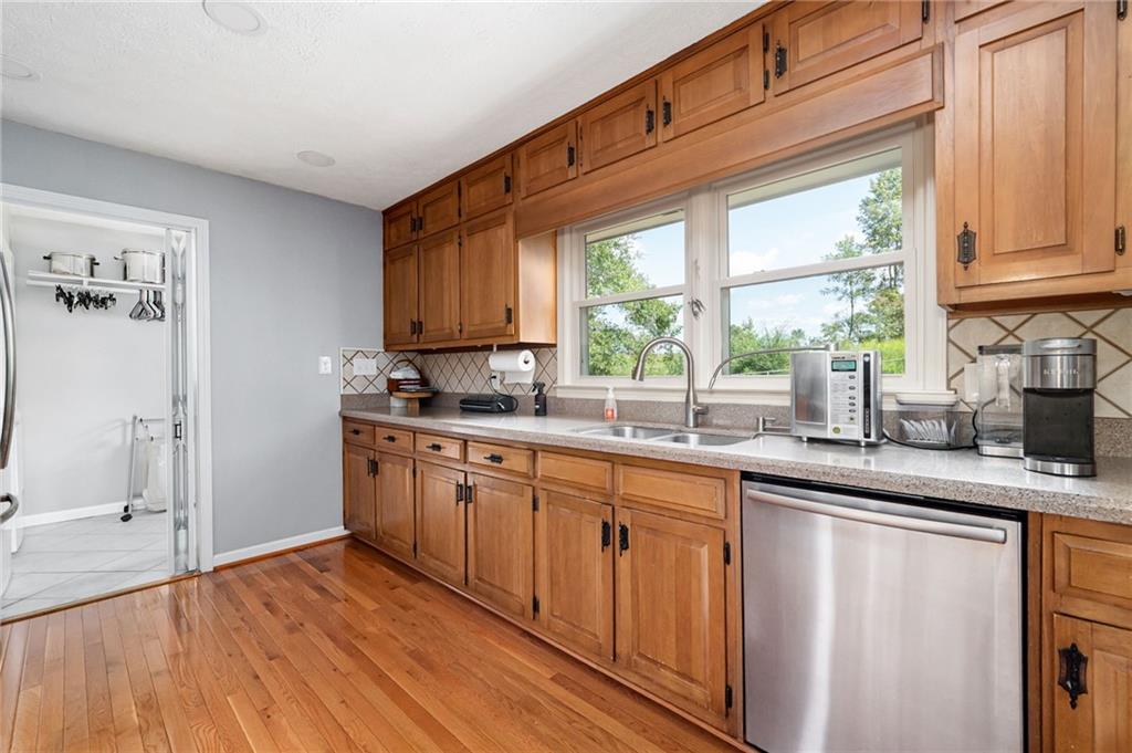 Kitchen with warm wood cabinets, hardwood floors, and a double sink beneath two windows.
