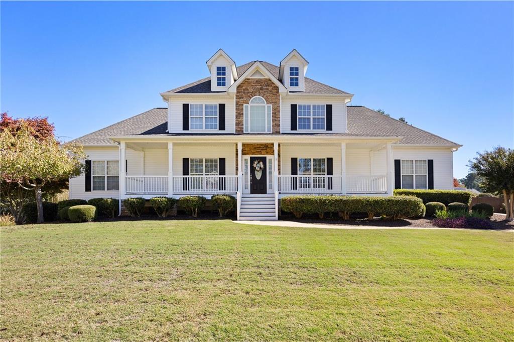 Two-story white house with brick accents, a wide covered porch, and a broad lawn.