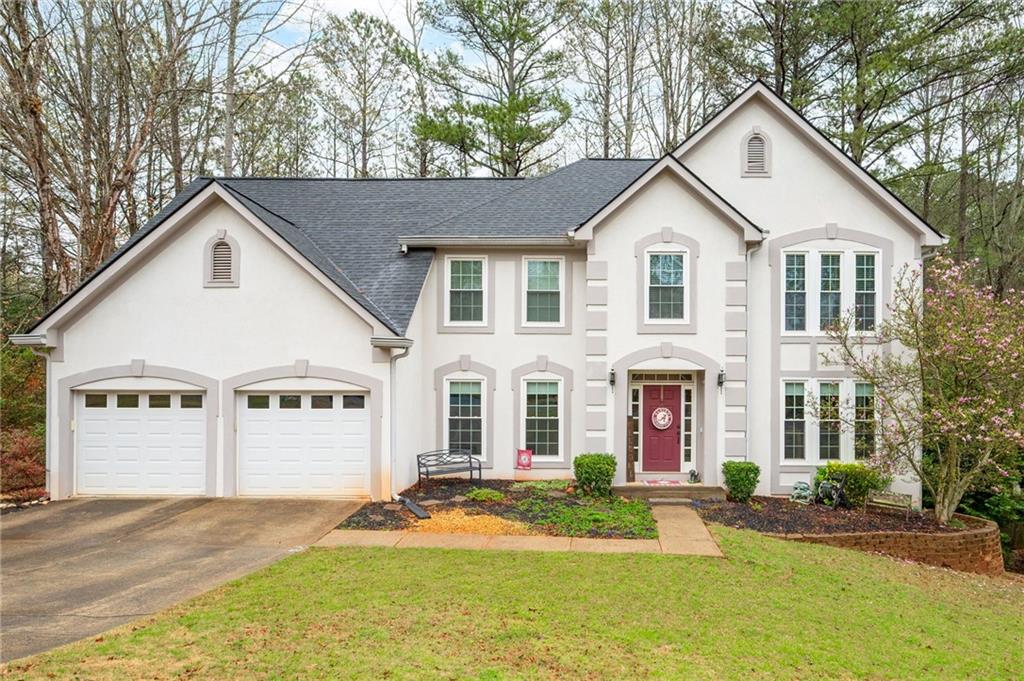 Two-story white house with a two-car garage and red front door
