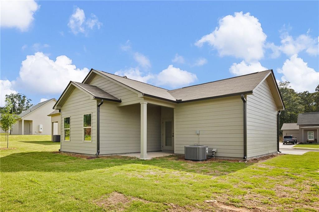Single-story beige house with a recessed covered entry, air-conditioning unit, and grassy yard.