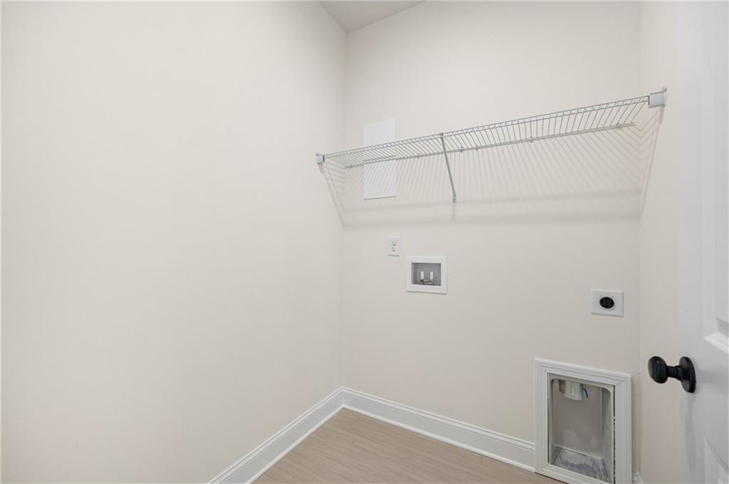 Empty laundry room with a wire shelf, washer hookups, and a small pet door.