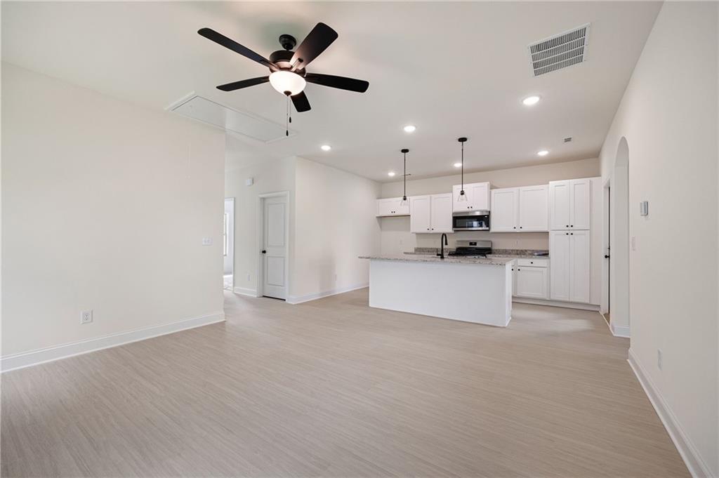 Open-plan kitchen with white cabinetry, a large island, and light wood-look floors.