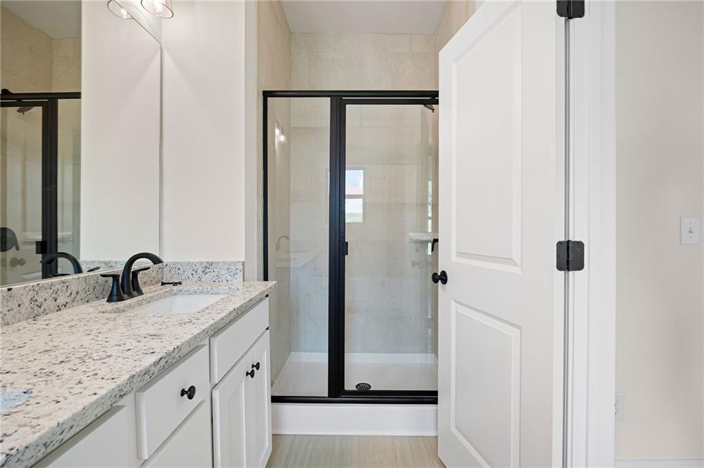 Bathroom with a granite vanity and black-framed glass shower.