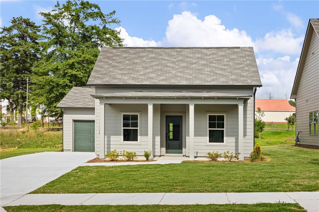 Light gray house with a covered porch, dark front door, attached garage, and lawn.
