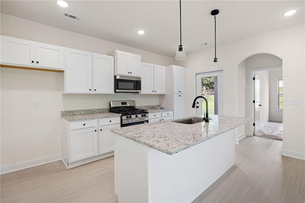 Bright kitchen with white cabinets, a granite island, and stainless steel appliances.