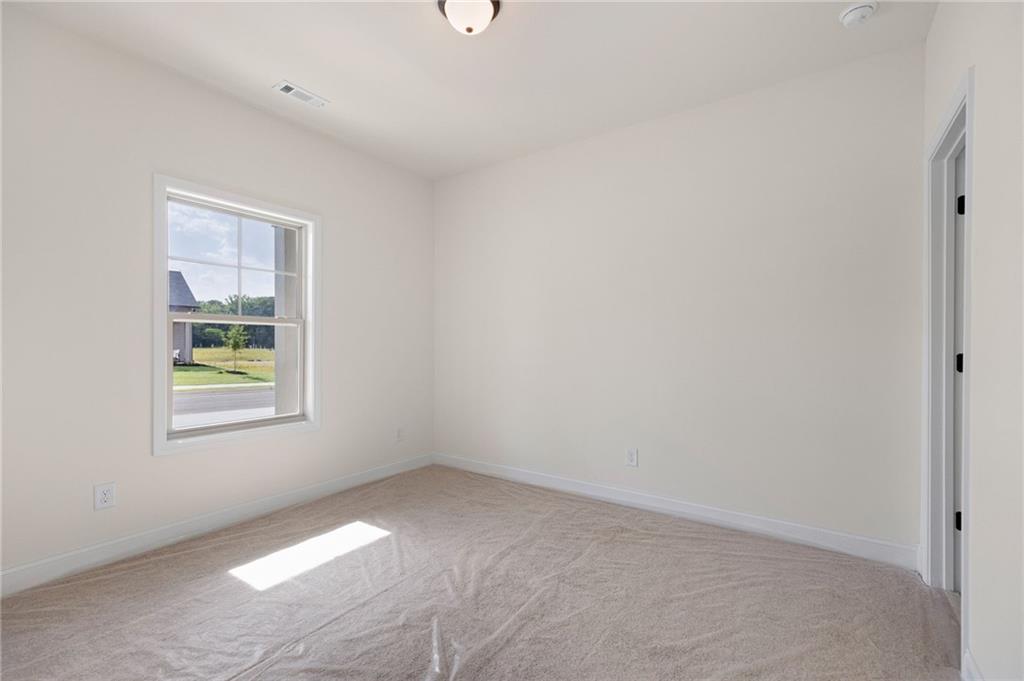 Empty carpeted bedroom with a single window overlooking the street.