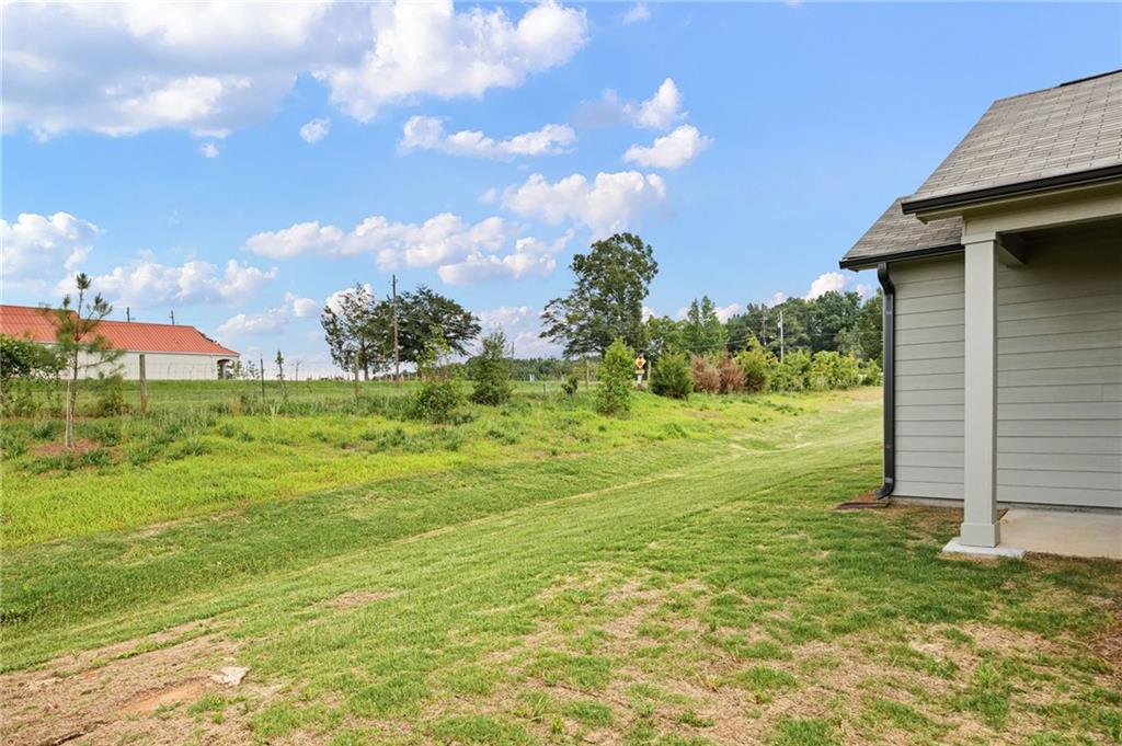Gray house beside a broad grassy yard and open field.