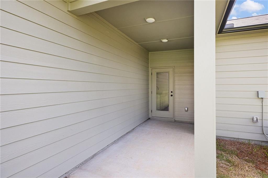 Covered concrete porch with a glass-paneled exterior door and light horizontal siding.