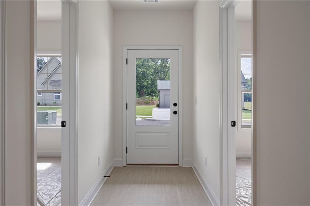 Entry foyer with a glass-panel front door, light flooring, and open doorways to adjoining rooms.