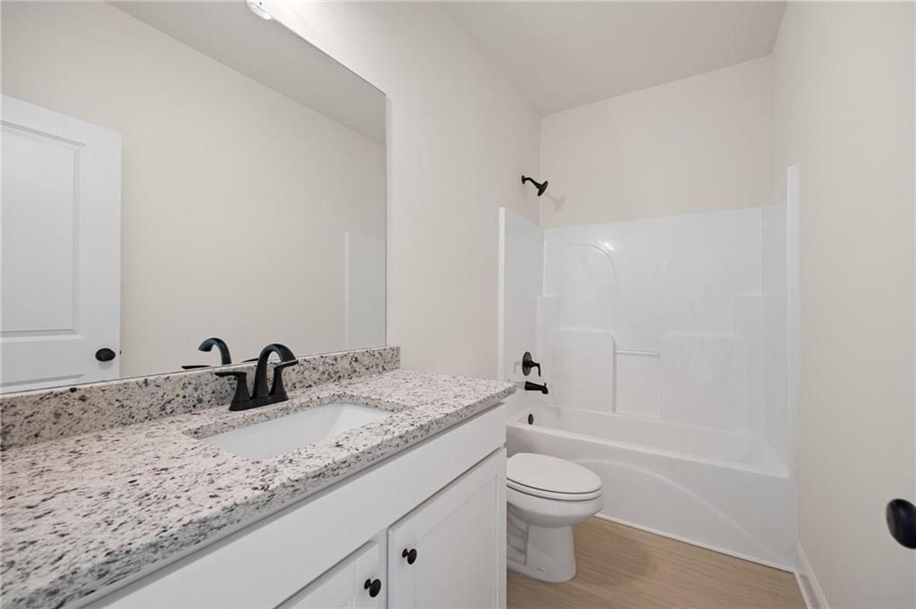 Bathroom with a speckled granite vanity, black faucet, and white tub-shower combination.