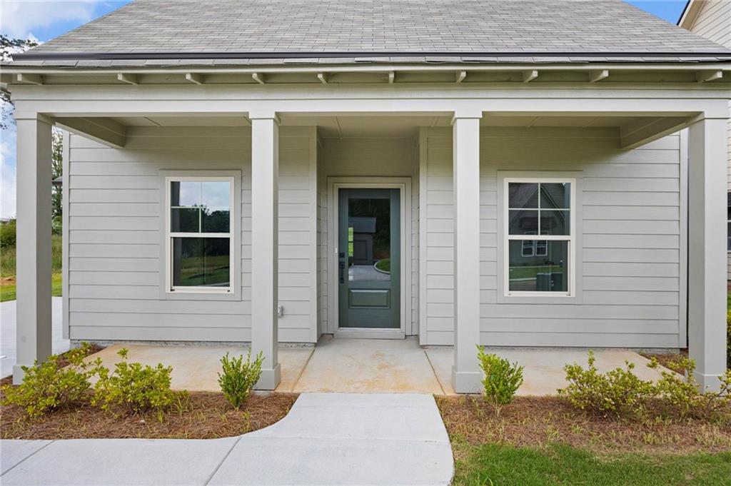 Light gray house with a covered porch, white columns, and a curved walkway to the front door.