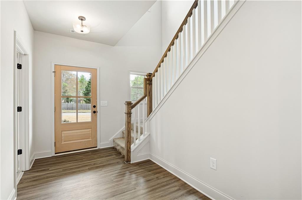 Entry foyer with a wood-and-glass front door and staircase with white balusters.