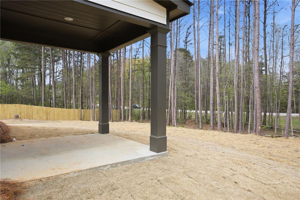 Covered concrete patio overlooking a fenced, wooded backyard.