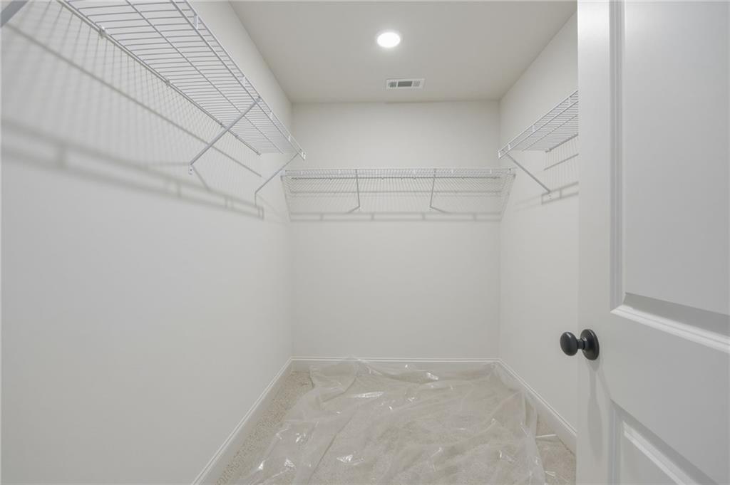 Walk-in closet with wire shelving on three sides and protective plastic covering the floor.