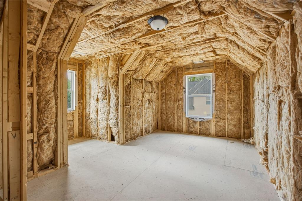 Unfinished room with exposed framing, insulated vaulted ceiling, and two windows.