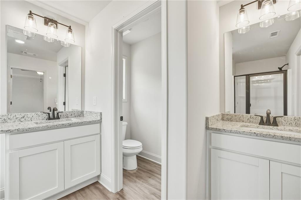 Bathroom with double vanities, stone countertops, and a separate toilet alcove.