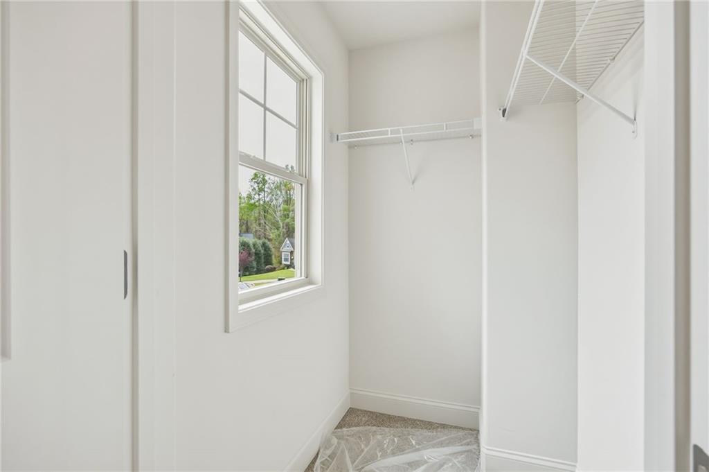Walk-in closet with white wire shelving, a window, and carpeted flooring.