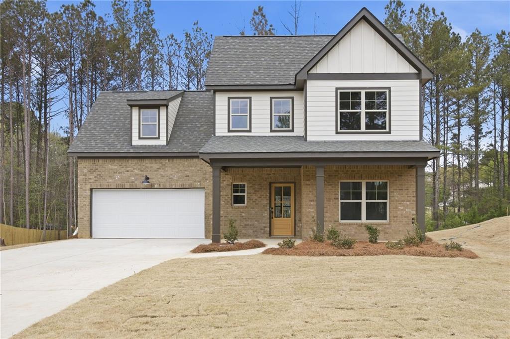 Two-story brick and white-sided house with a covered porch and attached garage.