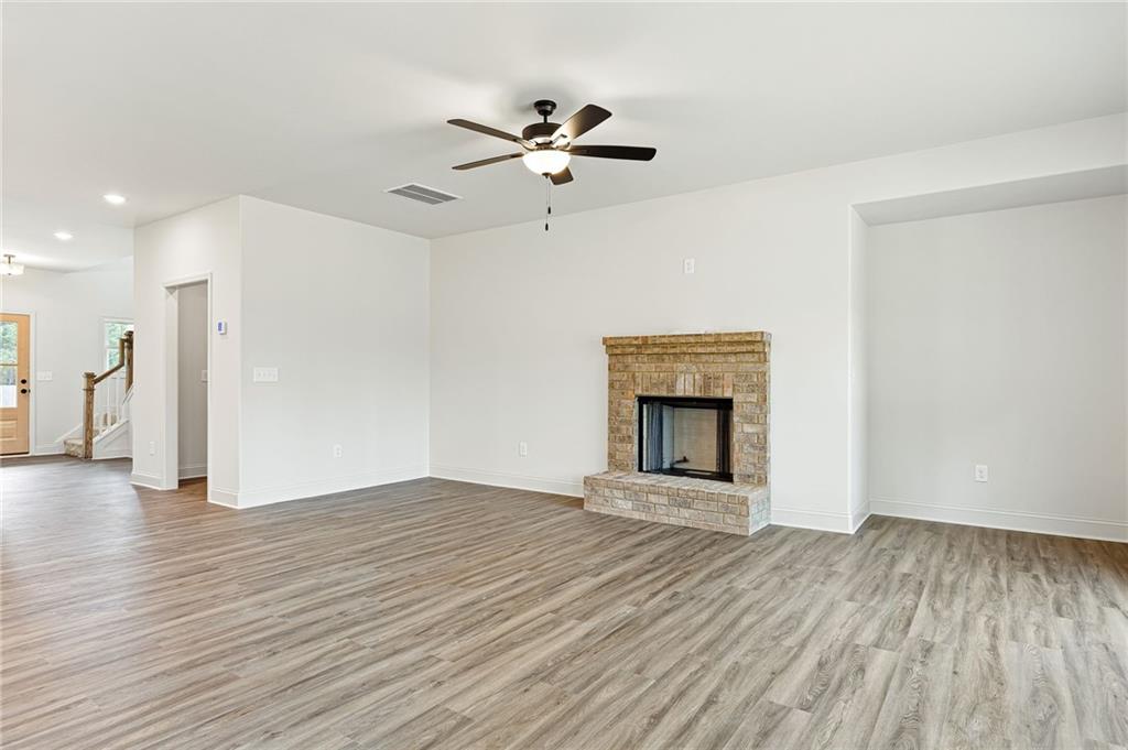 Unfurnished living room with a brick fireplace and gray wood-look flooring