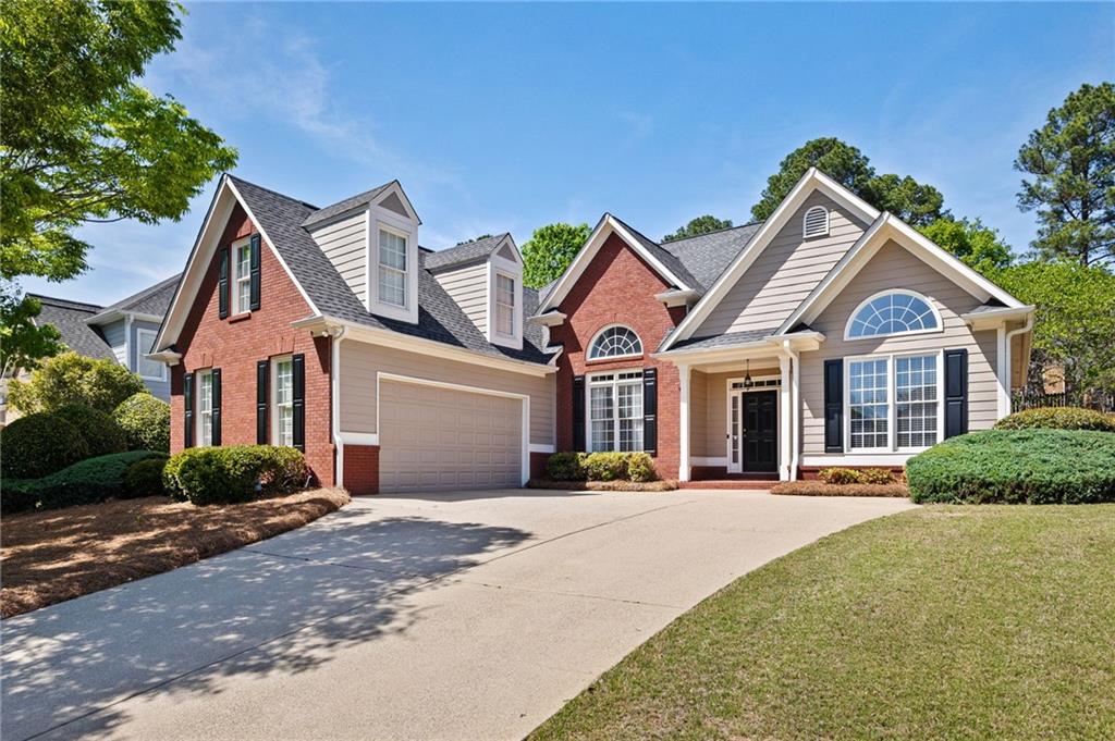 Brick-and-siding home with dormers, an attached garage, and a broad driveway.
