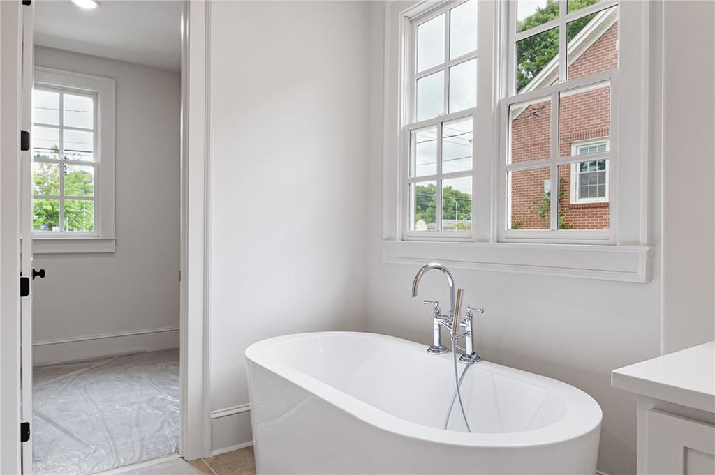 Bright bathroom with an oval soaking tub beneath tall divided-pane windows.